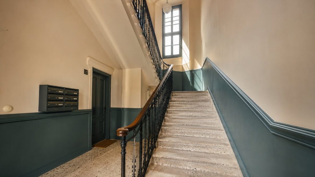 Escalera de comunidad de vecinos pintada con zócalo en dos tonos en Cambrils